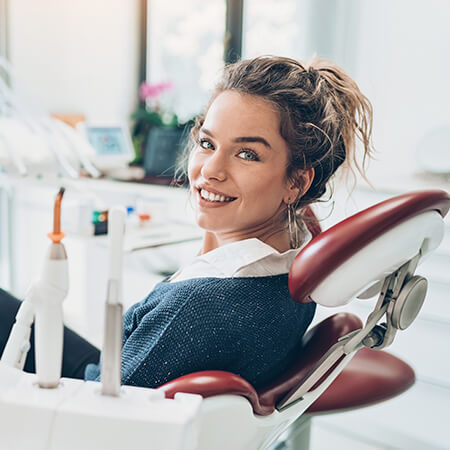 A young woman sitting in a red dentist chair